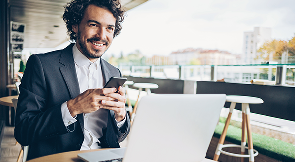 A business professional using multiple devices at a small table stock photo